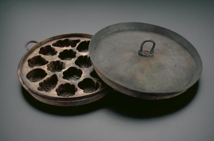 <a href="https://www.roots.gov.sg/Collection-Landing/listing/1070406"><strong>Brass ‘kueh baulu’ mould with lid</strong></a><br>
2006-01419<br>
1950s<br>
Collection of National Museum of Singapore, National Heritage Board